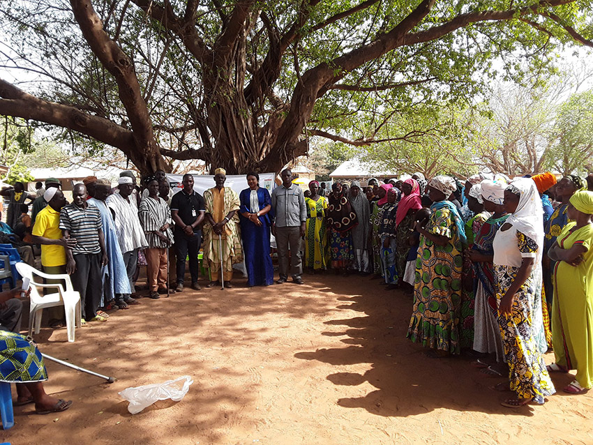 A group of 50 members of a local community in Ghana met on a public square, forming a semi-circle and commemorating International Migrants Day in 2018.